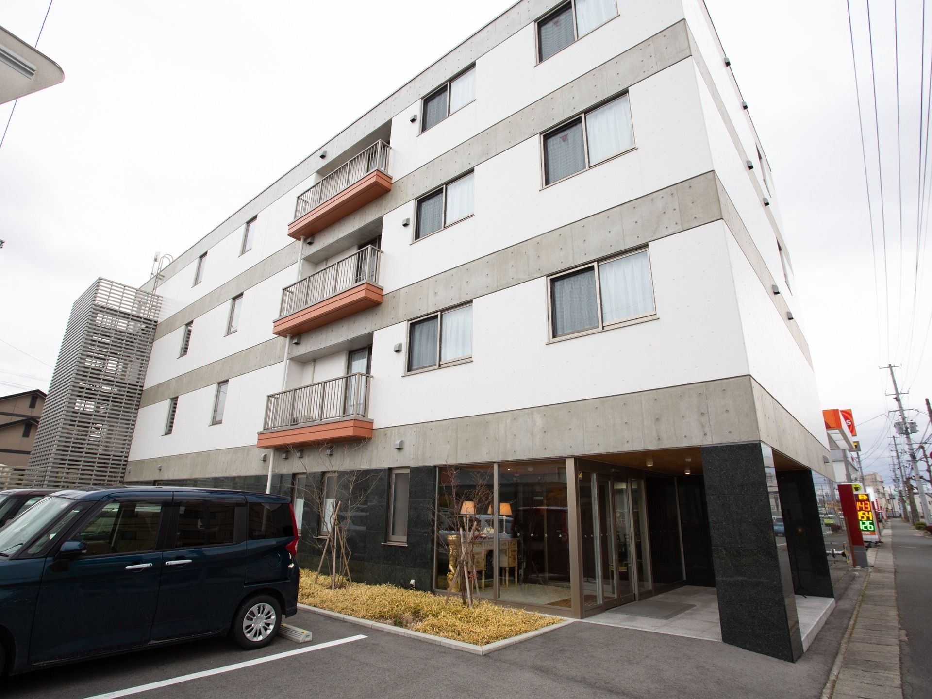 4階建ての施設。1階外壁は大理石のような質感。2階以上はコンクリートと白い壁が組み合わさっている。非常用階段が設けられている。