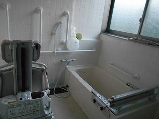 タイル張りの浴室には一人用の浴槽が設置され、リフトも置かれている。手すりも付き、大きな窓もある。