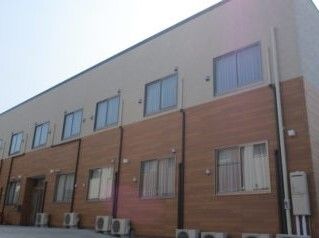 1階部分がブラウン、2階部分がベージュの２階建ての建物。横に長く、窓が多く付いている。