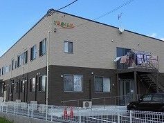 １階部分がダークブラウン、2階部分がベージュの外壁で2階建て。敷地内には駐車スペースもある。