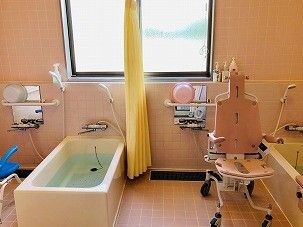 カーテンが中央に設置された広い浴室の右側にはレール付きの浴槽、左側には一人用の浴槽がある。