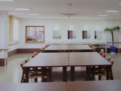 大きな木製のテーブルセットが複数置かれている広い共有スペース。壁には手すりが付き、観葉植物も置かれている。