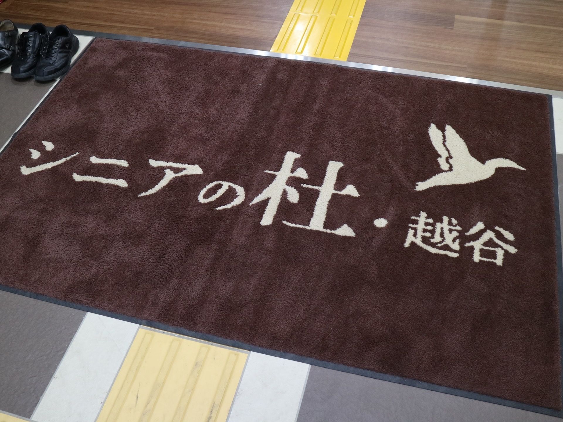 玄関を入ると、施設名が大きく書かれたカーペットが出迎えてくれる。点字ブロックの凹凸は阻害しないように注意されている。