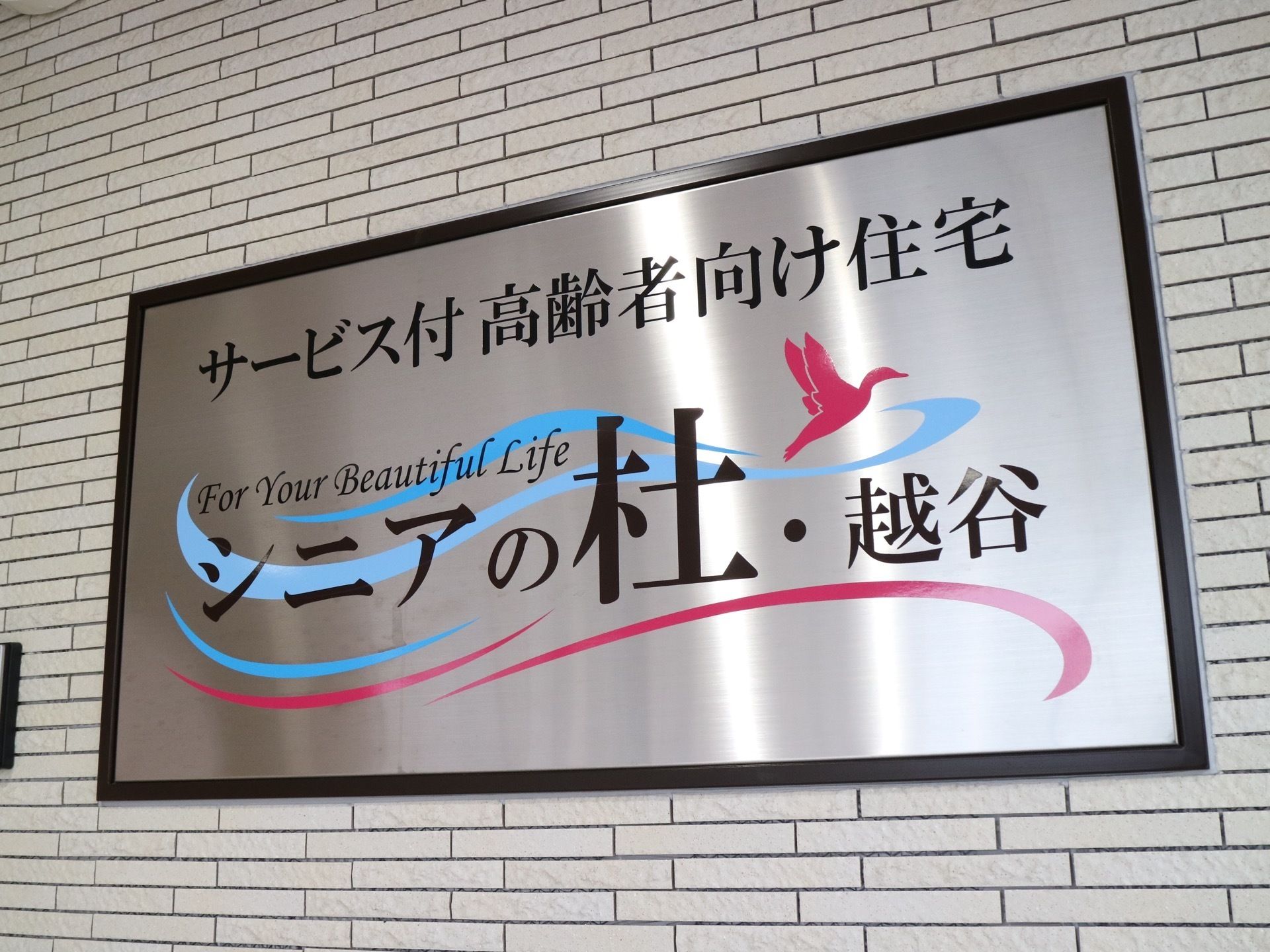 エントランスの壁には、きれいな施設の表札がある。施設名とともに、施設のコンセプトをあらわすようなイラストと言葉が描かれている。