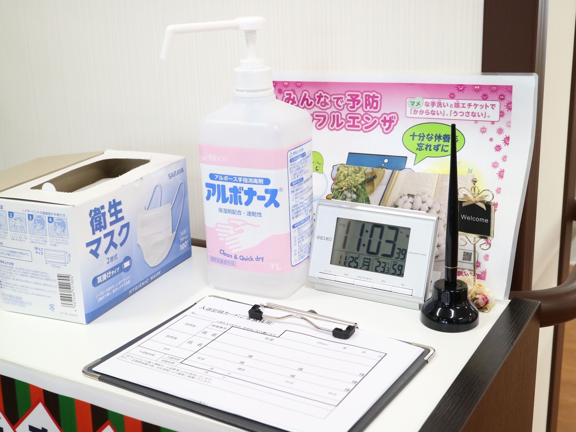 玄関に設けられた来訪者様用のコンパクトな記帳台。専用の黒いペン立て、そしてポンプ入りの消毒液が用意されている。