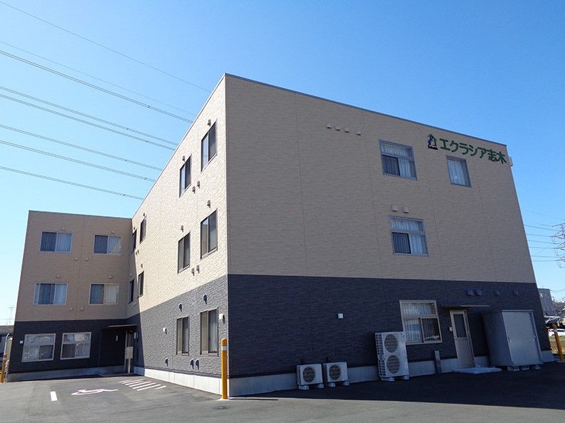 広い駐車スペースがある、ツートンカラーの外壁の3階建て建築物