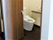 シックな色合いのドアの向こう側にモダンなデザインのトイレが見えている様子