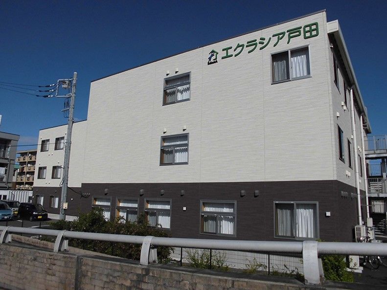 エクラシア戸田と書かれている、ツートンカラーの外壁の3階建て建築物
