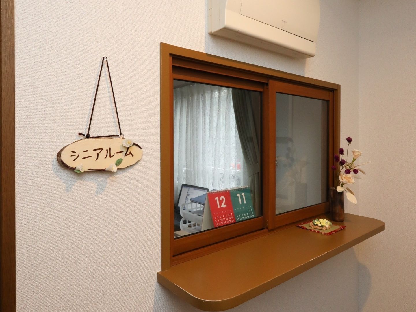 木製の枠がついた窓があり、カウンターが設置されている。窓の内側には、カレンダーが置かれており、カウンターには飾りがある。