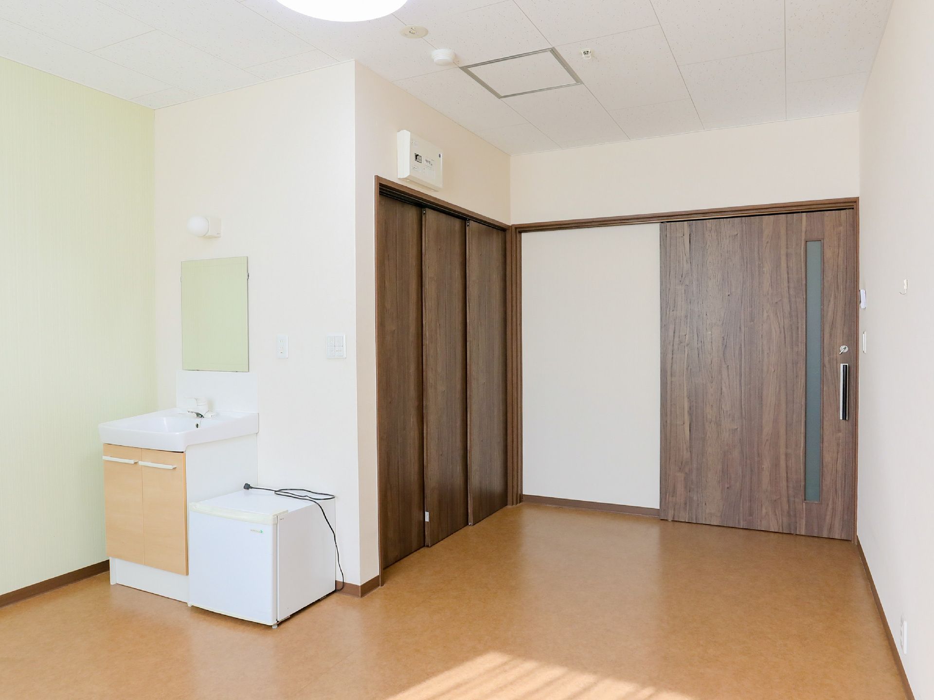 なにかを見て笑顔で手をたたいている高齢女性とスタッフの様子。施設での一場面の写真