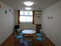 大きな窓が付いた談話スペースには円形のテーブルセットが置かれ、テレビやエアコンが設置されている。