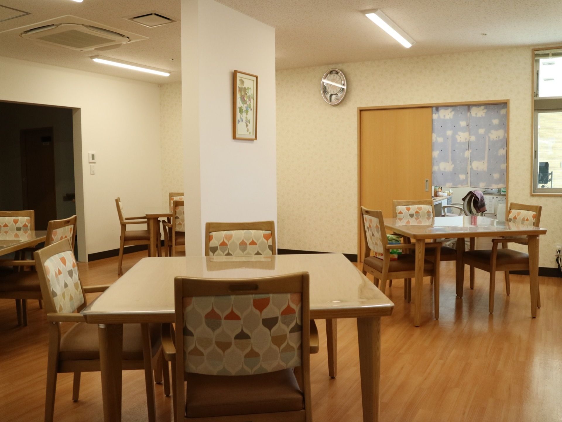食堂の椅子の背もたれには落ち着いた色調の柄が描かれている。天井埋め込み式のエアコンがある。