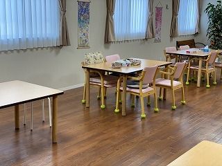 木製のダイニングテーブルが複数置かれた食堂には大きな窓がたくさんあり、タペストリーや観葉植物も飾られている。