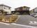 敷地を入ったところには駐車場があり、右側のスペースに車が数台停められている。手前にある花壇の中に、施設名が書かれた看板が立っている。