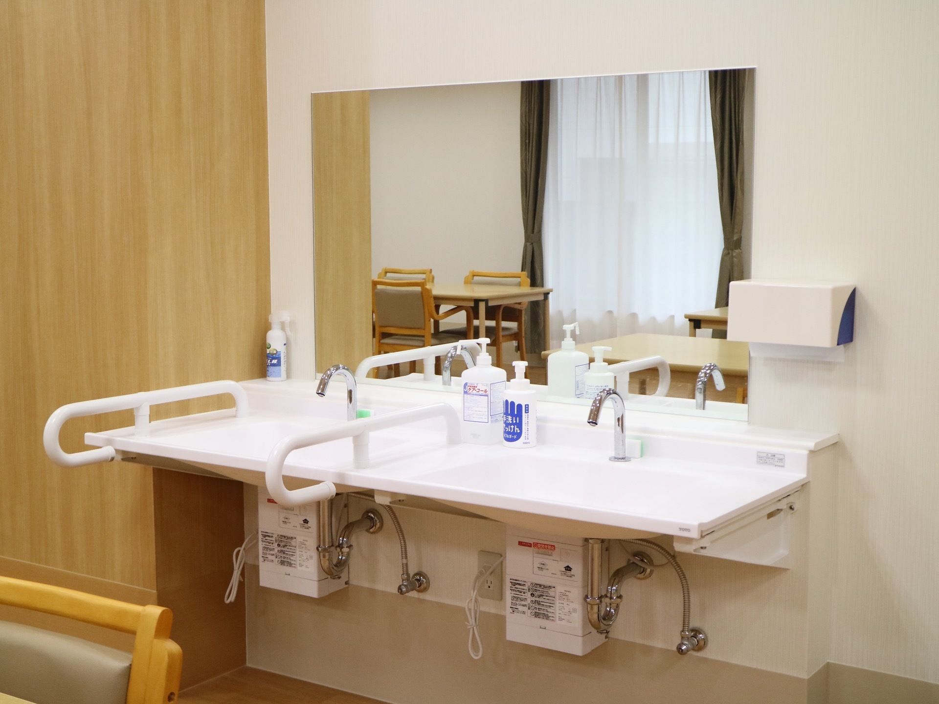 テーブルが並んだフロアの一角に洗面台が2カ所設置されている。大きな鏡が付いており、手すりがある。