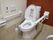 便座の両脇に手すりが備え付けられたトイレがある。壁には洗浄ボタンの他、ナースコールも設置されている。