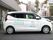 ホームの建物の脇に舗装された駐車スペースがあり、車が数台停まっている。一番手前には施設の白い専用車がある。