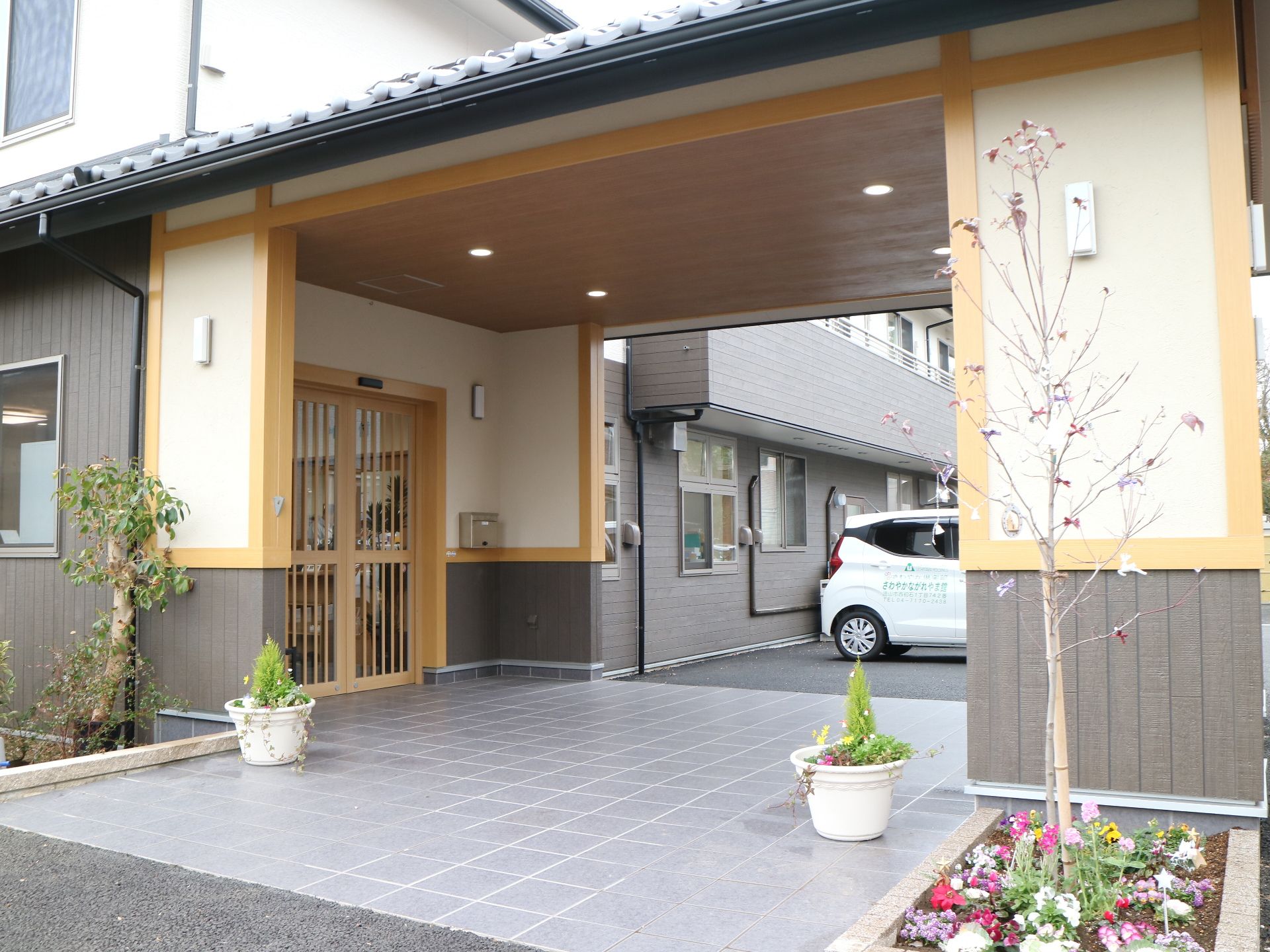 白壁に瓦屋根という和風の建物。周辺には木も多く植えられ、家庭的な雰囲気。