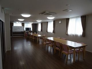 大きな窓がたくさん付いたフローリングの部屋には、木製のダイニングテーブルが複数置かれている。