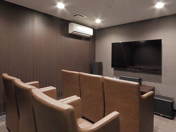 大きなテレビが設置された部屋にはエアコンが付き、ブラウン系の一人用の椅子が整列している。
