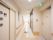 通路の壁は白と薄いグレーのストライプ柄になっている。左にはトイレのマークが描かれたドアがあり、丸いすりガラスが3つ付いている。