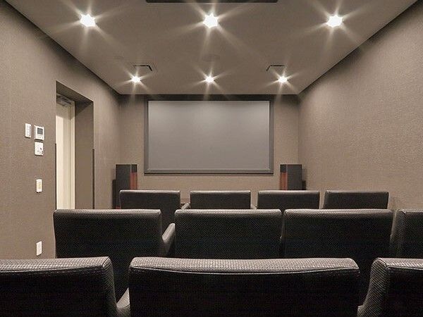 黒い一人用の椅子がずらりと並べられているシアタールーム。前には大きなスクリーンが設置されている。