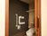 個室トイレの扉が開いている。洋式便座が１台あり、アームレストが上がった状態になっている。壁にナースコールがある。