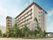 桜の花が咲いた木など、緑に囲まれたマンション。各フロアにベランダが付き、ベージュでまとめられている。