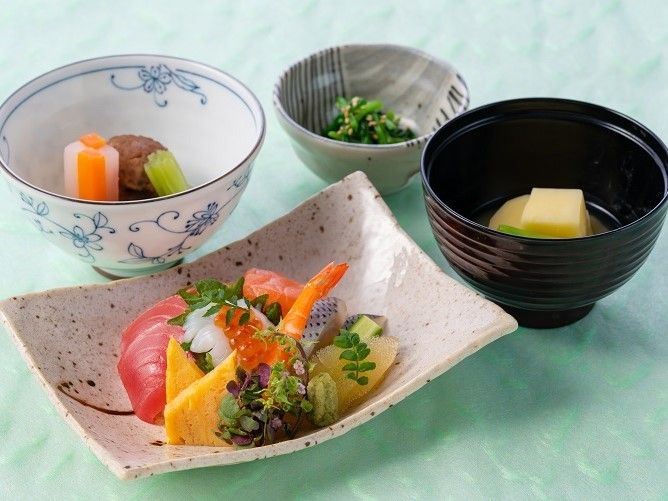 彩りのきれいな食事。刺し身や吸い物、野菜の和え物などが写る。