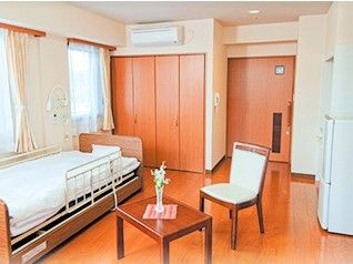 収納設備やベッド、いす、小さなテーブルが写っている施設内の居室の様子