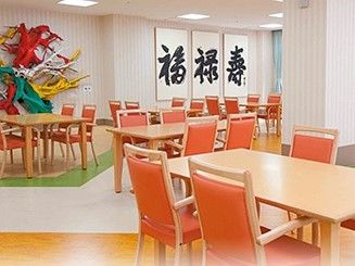 福禄寿の飾りつけがしてある施設のリビング。複数人が座れるテーブルと椅子が置いてある
