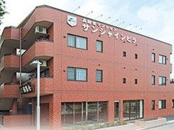赤い壁が印象的な鉄骨造の建物の外観写真。高齢者マンションの外観