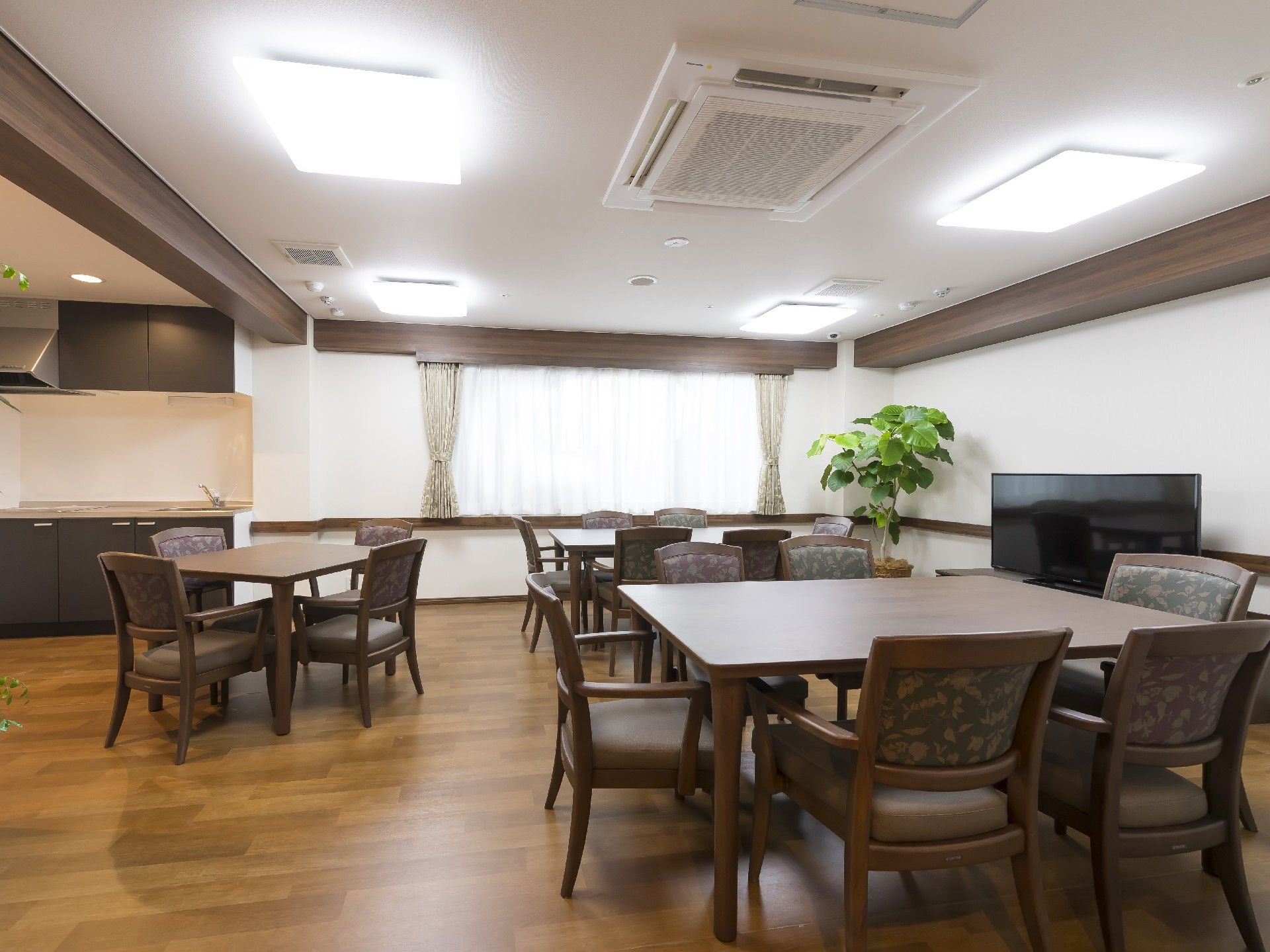 ブラウンのダイニングテーブルが複数置かれた食堂にはテレビも設置されている。