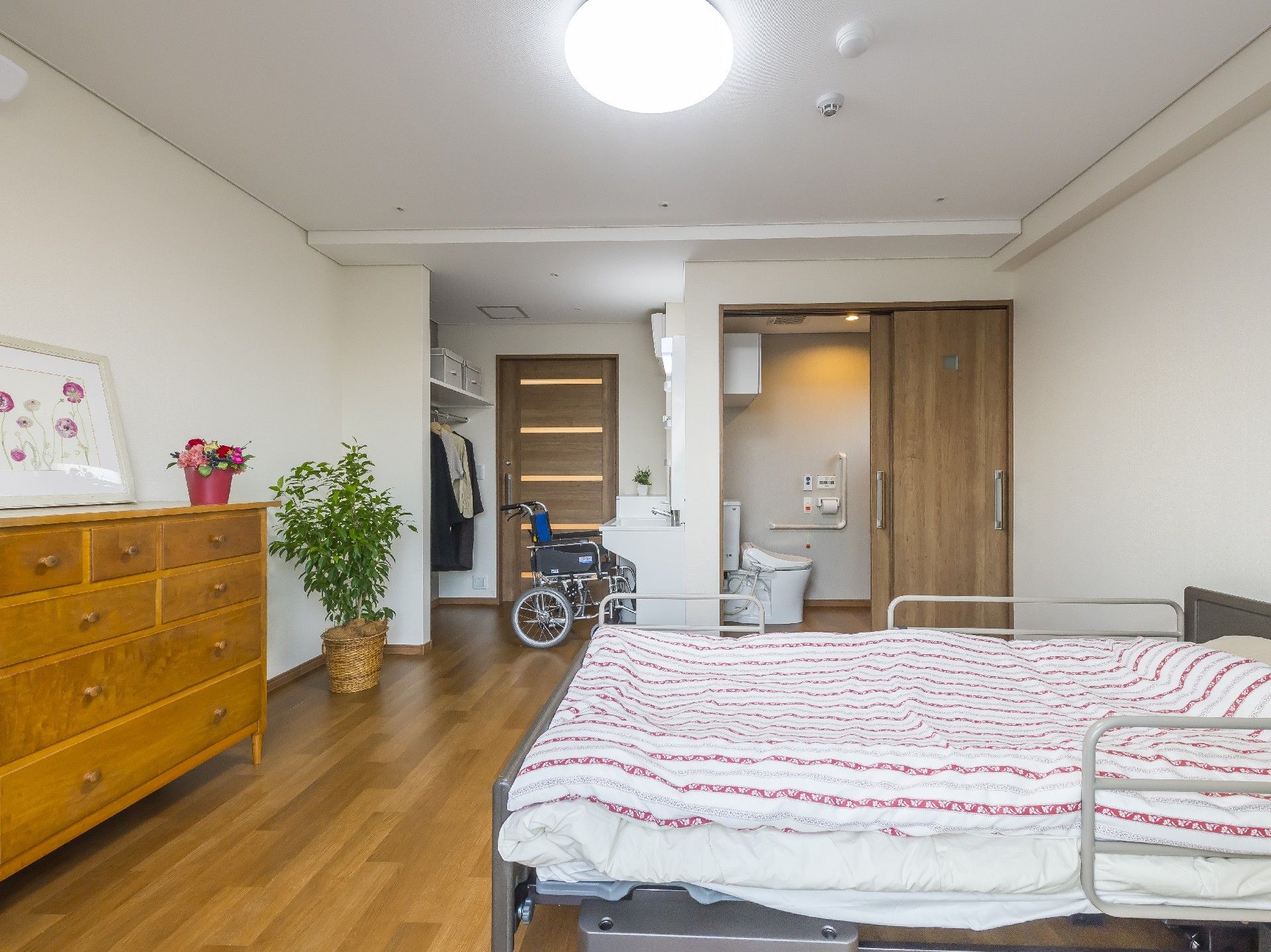 トイレが付いたシンプルな居室には寝具用のベッドやタンスが置かれている。