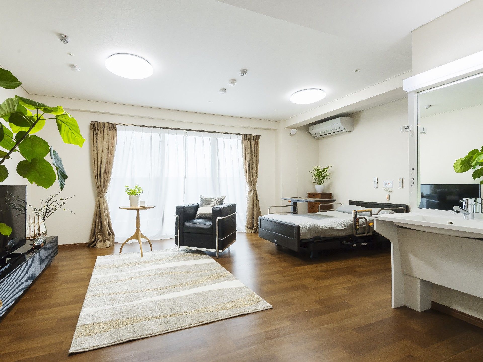 大きな窓が付いたフローリングの部屋にはベッドやカーペット、一人用のソファなどがある。