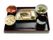 黒いトレーに並べられた食事。炊き込みご飯に汁物、メインの魚料理にあえ物など。