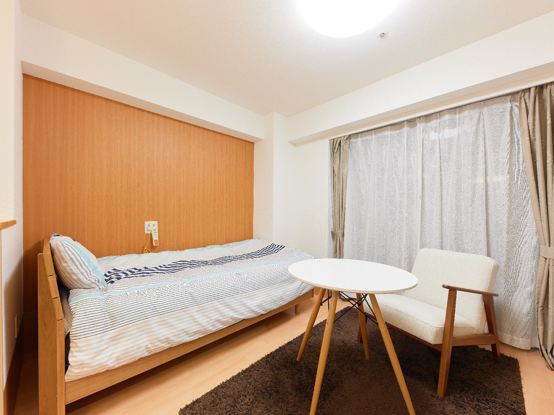 ベッドサイドには緊急通報装置が付いた一人用の部屋には寝具付きのベッドやテーブルセットがあり、大きな窓もある。