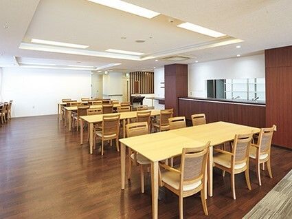 木製のダイニングテーブルが並べられたスペース。左側にはカウンター席もあり、右側には厨房もある。