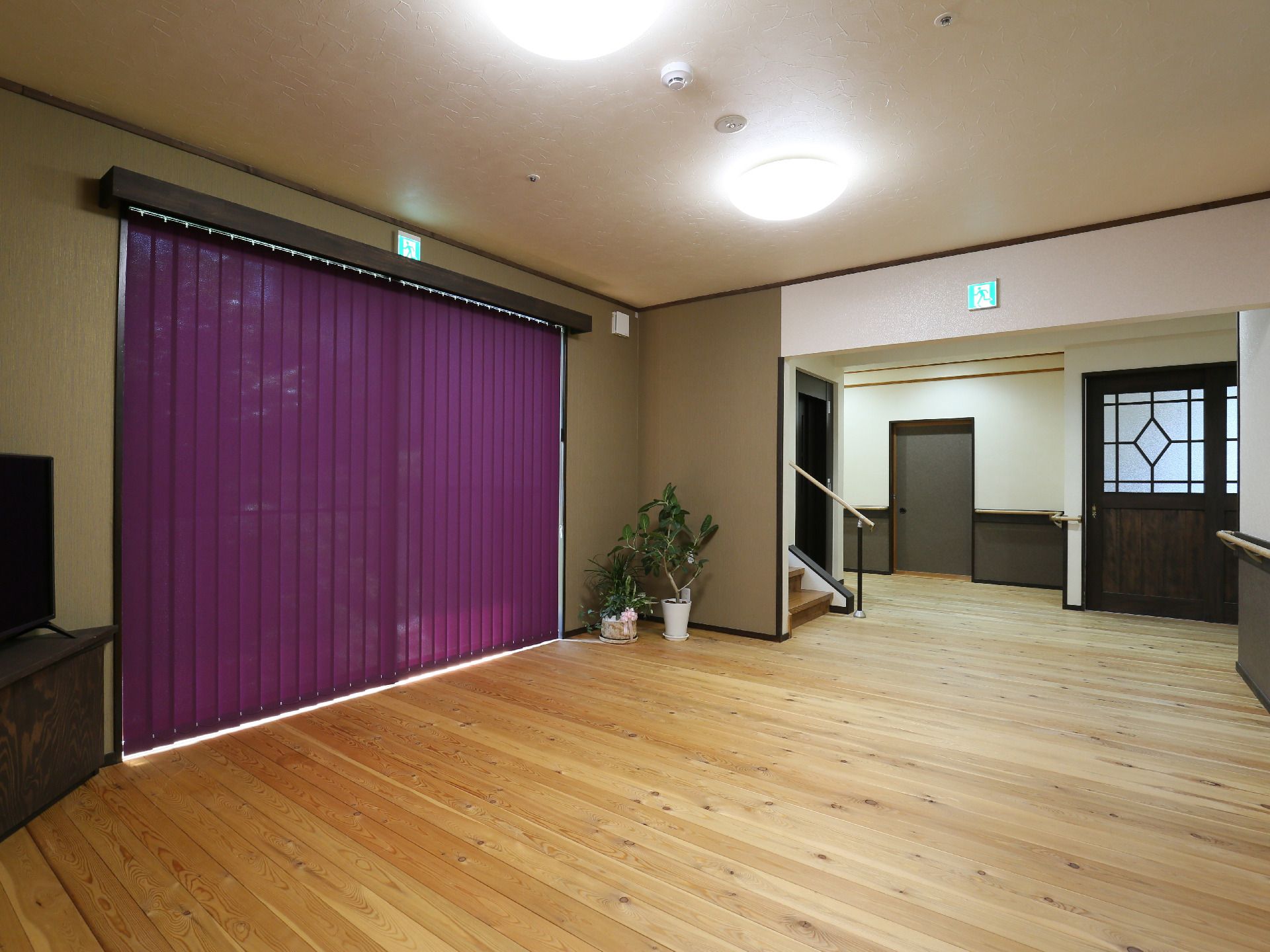 パジャマ姿でベッドに横になっている高齢女性に笑顔で介護に当たるエプロン姿の女性スタッフ。