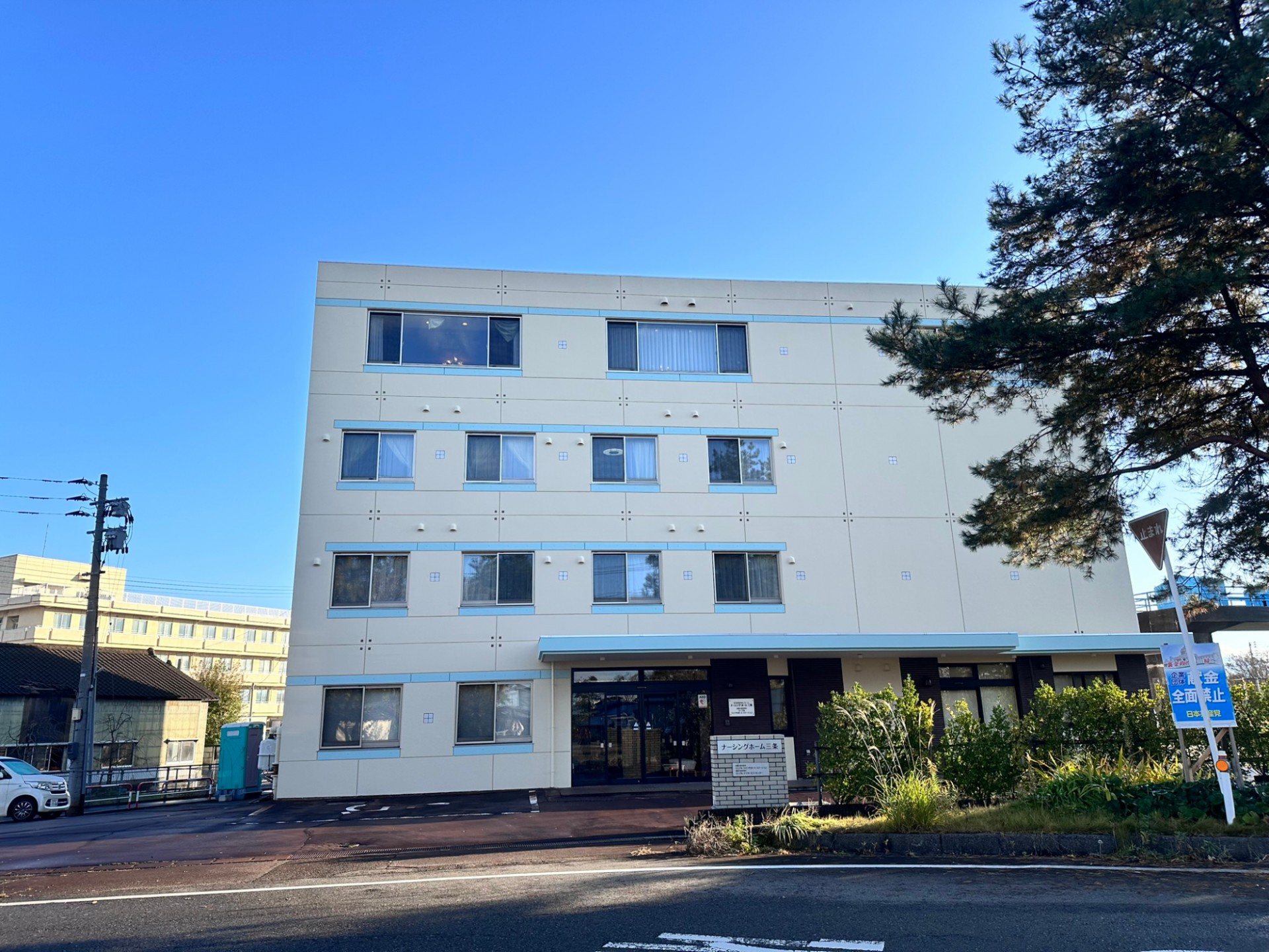 ４階建ての大きな建物で、玄関の上にはひさしがある。車椅子をご利用の方のために、玄関のすぐそばに専用駐車場をご用意している。