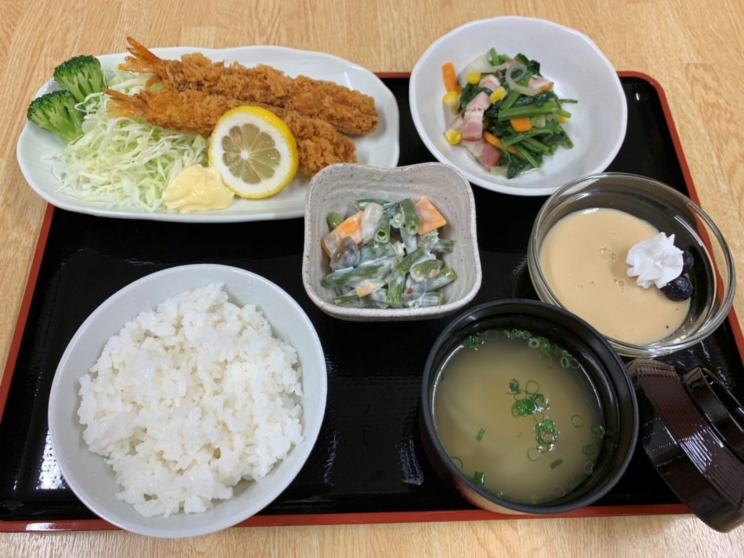 エビフライを主菜とする一汁三菜とデザートが並べられているトレイ