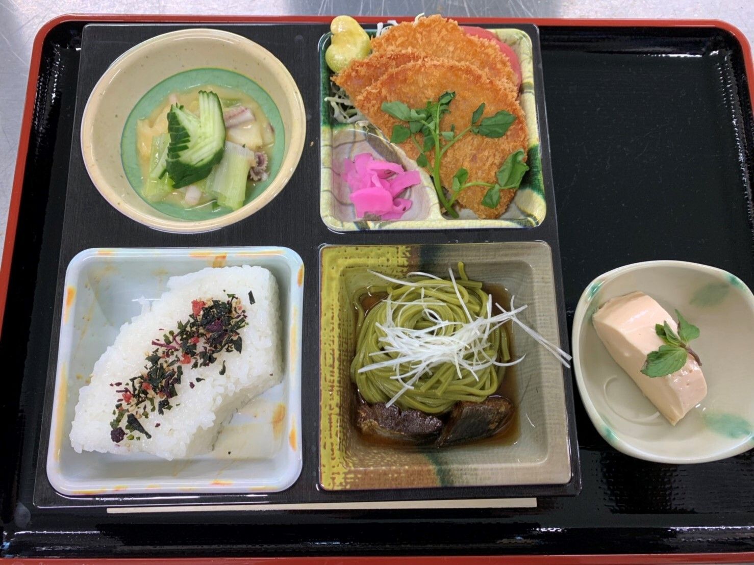 扇形のごはん、茶そば、おかずの小鉢とデザートからなる食事