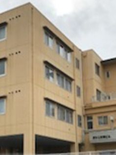 ベージュ系の建物は4階建てでどっしりとした造り。窓がたくさん付いていて、周りには建物はない。