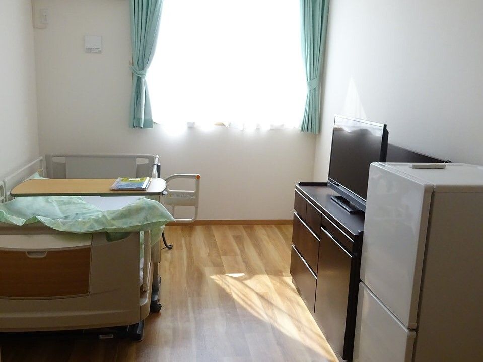 フローリングの部屋には家具や家電が置かれ、大きな窓が付いている。日当たりのいい部屋。