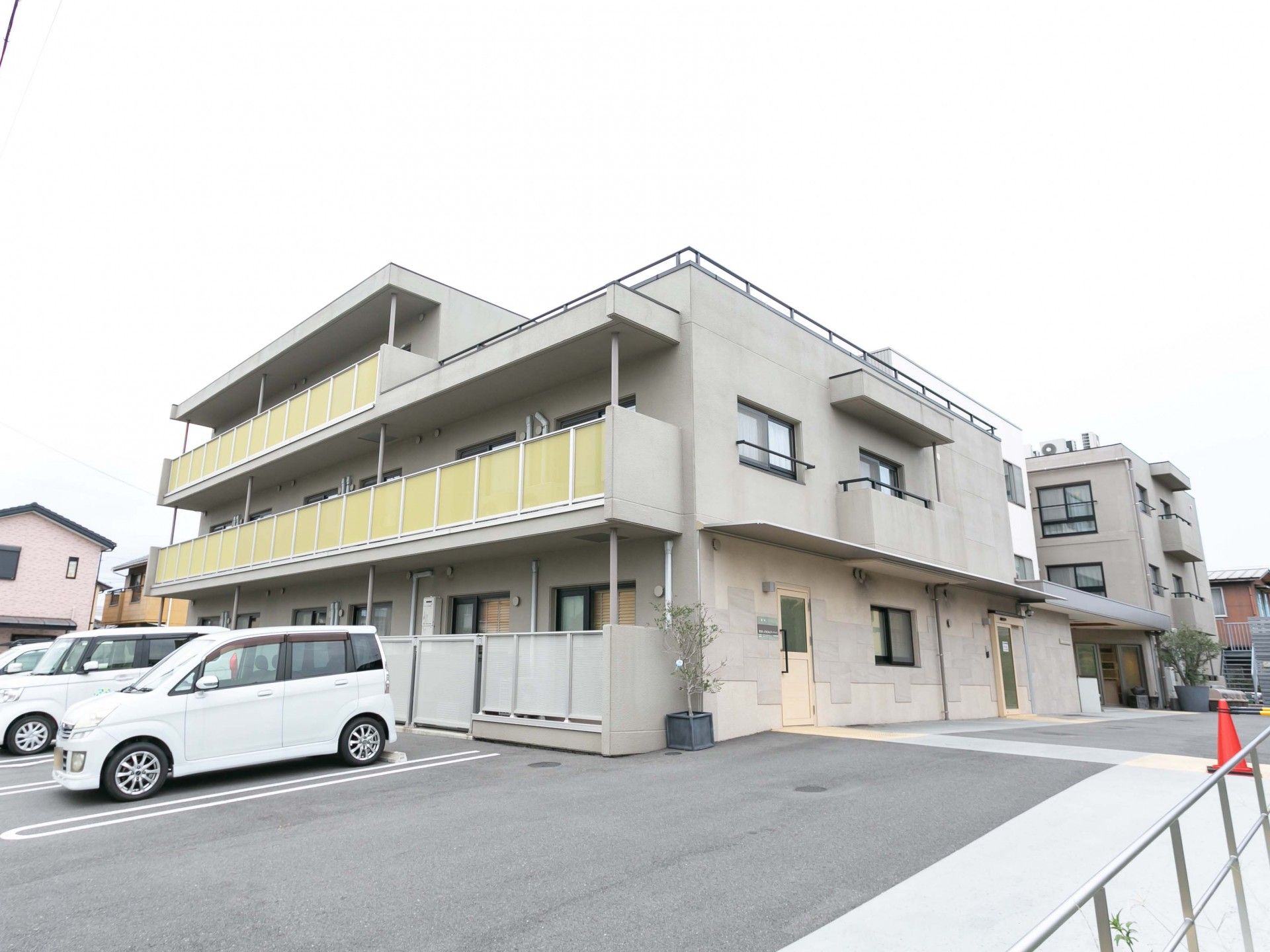 3階建ての建物の3階部分はほかの階よりも小さく、建物の前には広い駐車場がある。