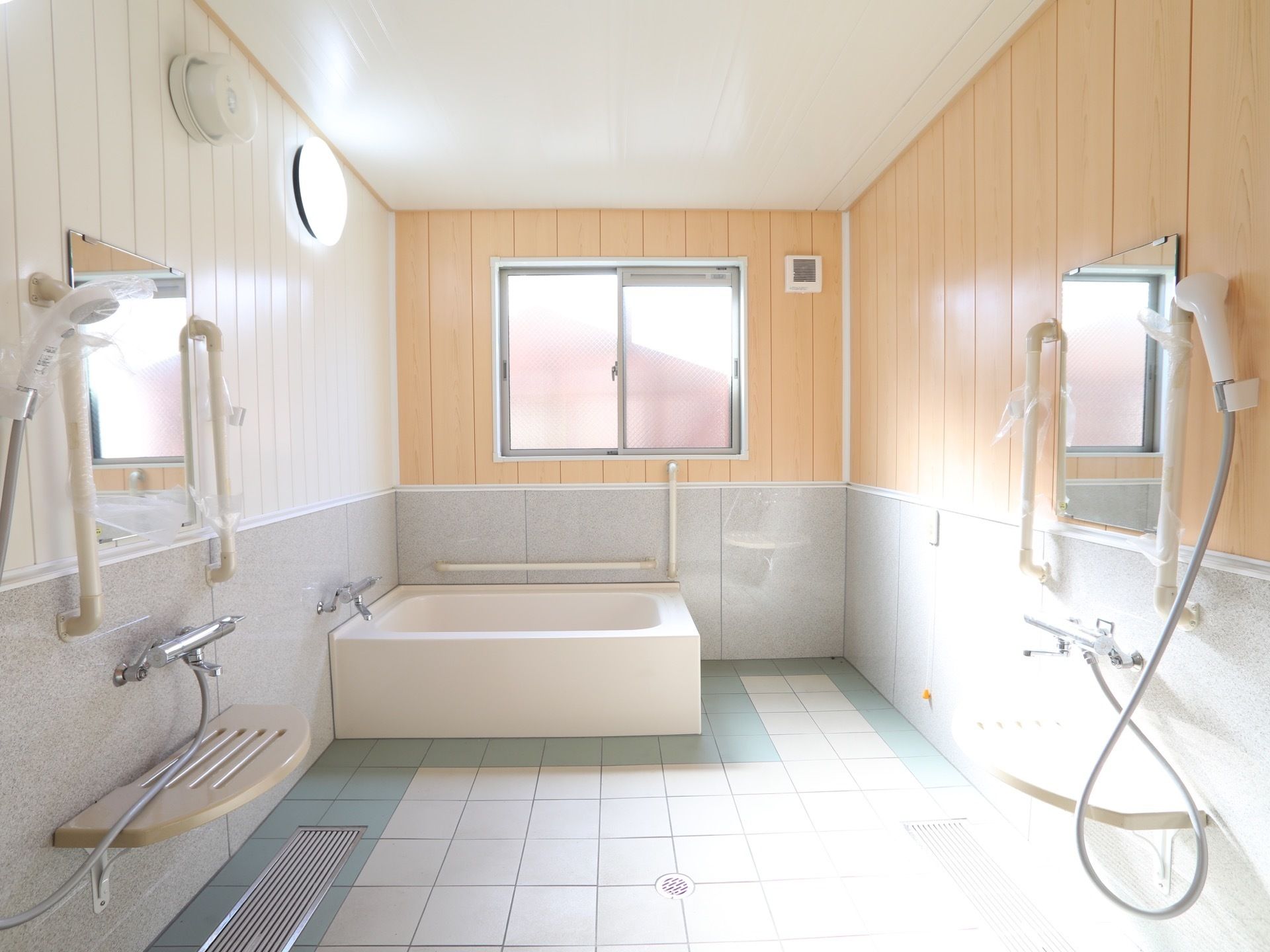 浴室内に洗い場が２つある。大きな窓からは光が差し込んでおり明るい。浴槽の周りにも手すりがある。
