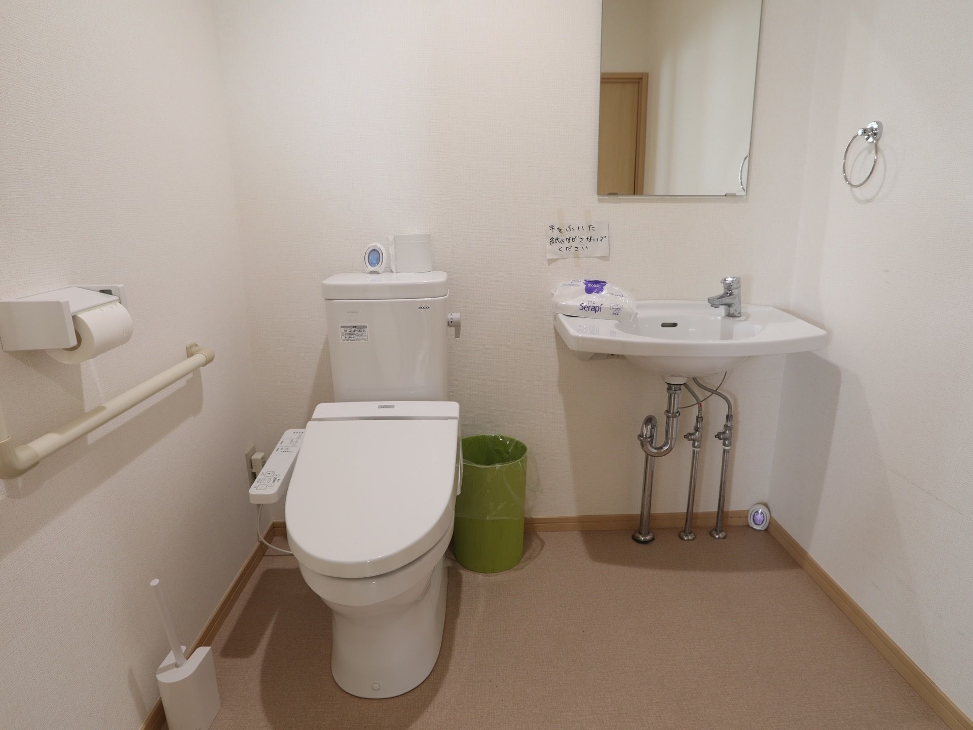 消臭剤が２個置かれているトイレである。洗面所が隣にあり、ペーパータオルがある。トイレ掃除の器具も備わっている。