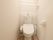 手洗い機能付きのトイレである。そばにタオルかけが設置してあり、突っ張り棒で棚が作られている。白く清潔感がある。