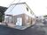 高い建物は周辺になく、近い場所に鬱蒼と茂った木々がみられる。ひさしの下に、パイプ椅子が２個並べて置かれている。