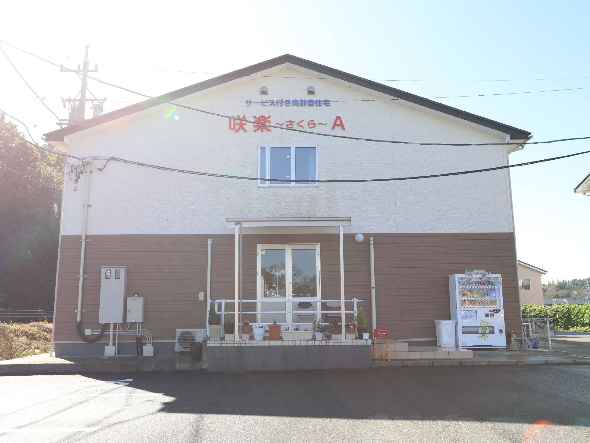 壁面に施設名称が明記されている２階建ての建物と舗装された駐車場
